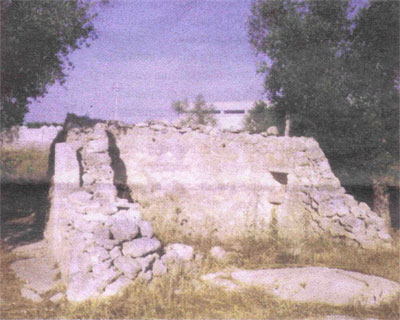 Foto di Cristiano Villani, del Menhir Santa Loja (2004). Il monolite sporge dal muro del rudere a sinistra, sul lato esposto all incirca a Nord della costruzione. La foto corrisponde alla vista che si aveva dalla ampia strada della zona industriale