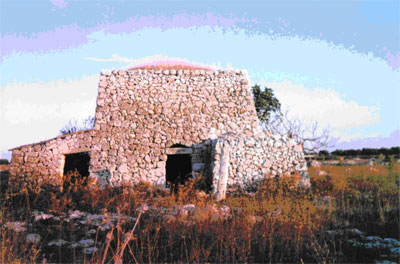 vista da Nord-Ovest del trullo e del Menhir Chipuru. Foto del 12/09/1993. Si noti il monolite alla destra dell' ingresso al corpo principale del trullo.